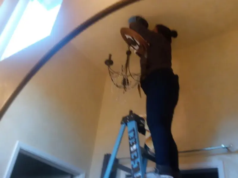 Electrician installing a chandelier in a North Baltimore residence